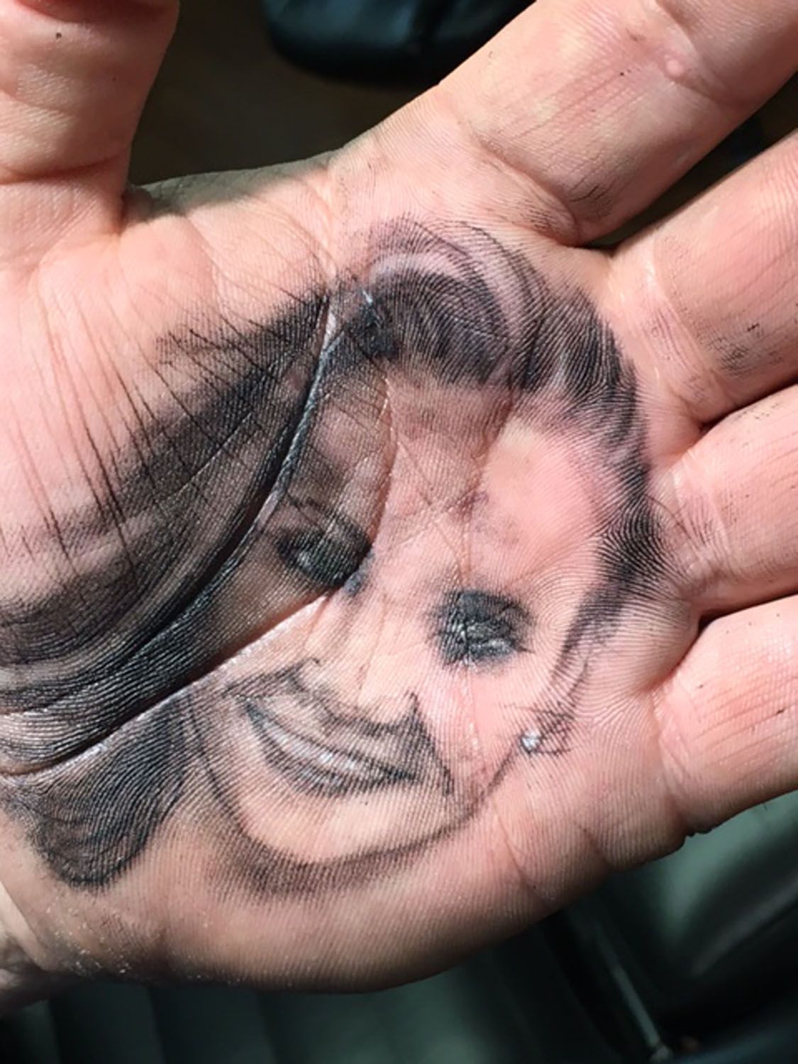 A close up of a person 's hand with a tattoo of a woman 's face on it.
