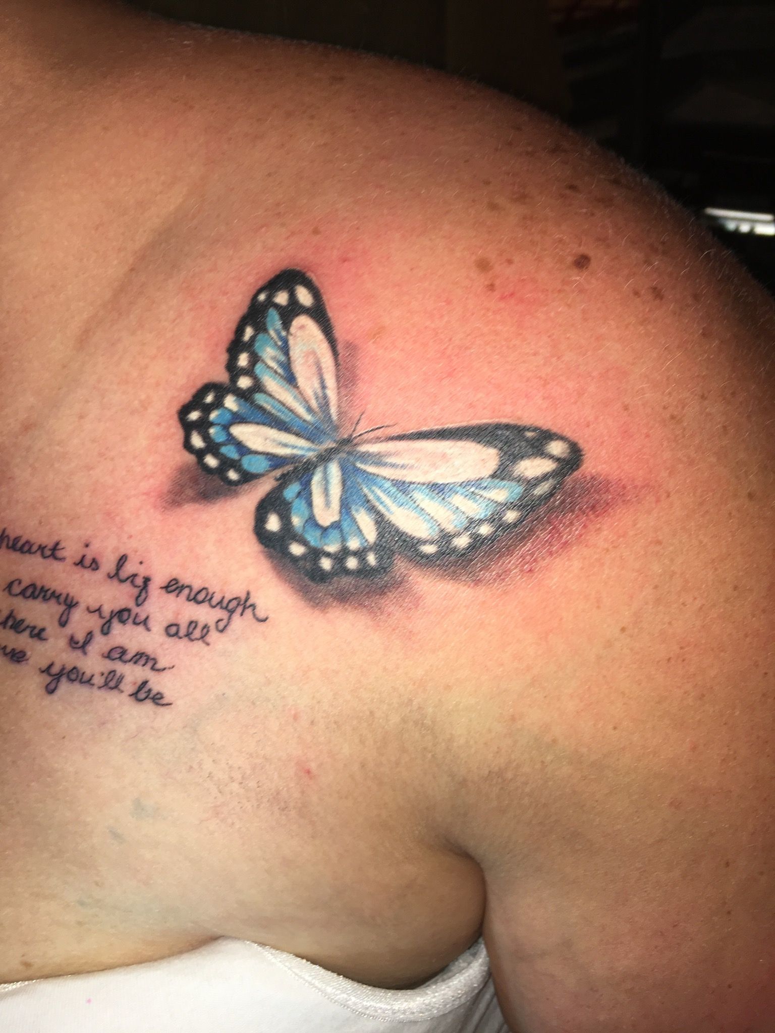 A woman has a blue butterfly tattoo on her shoulder.