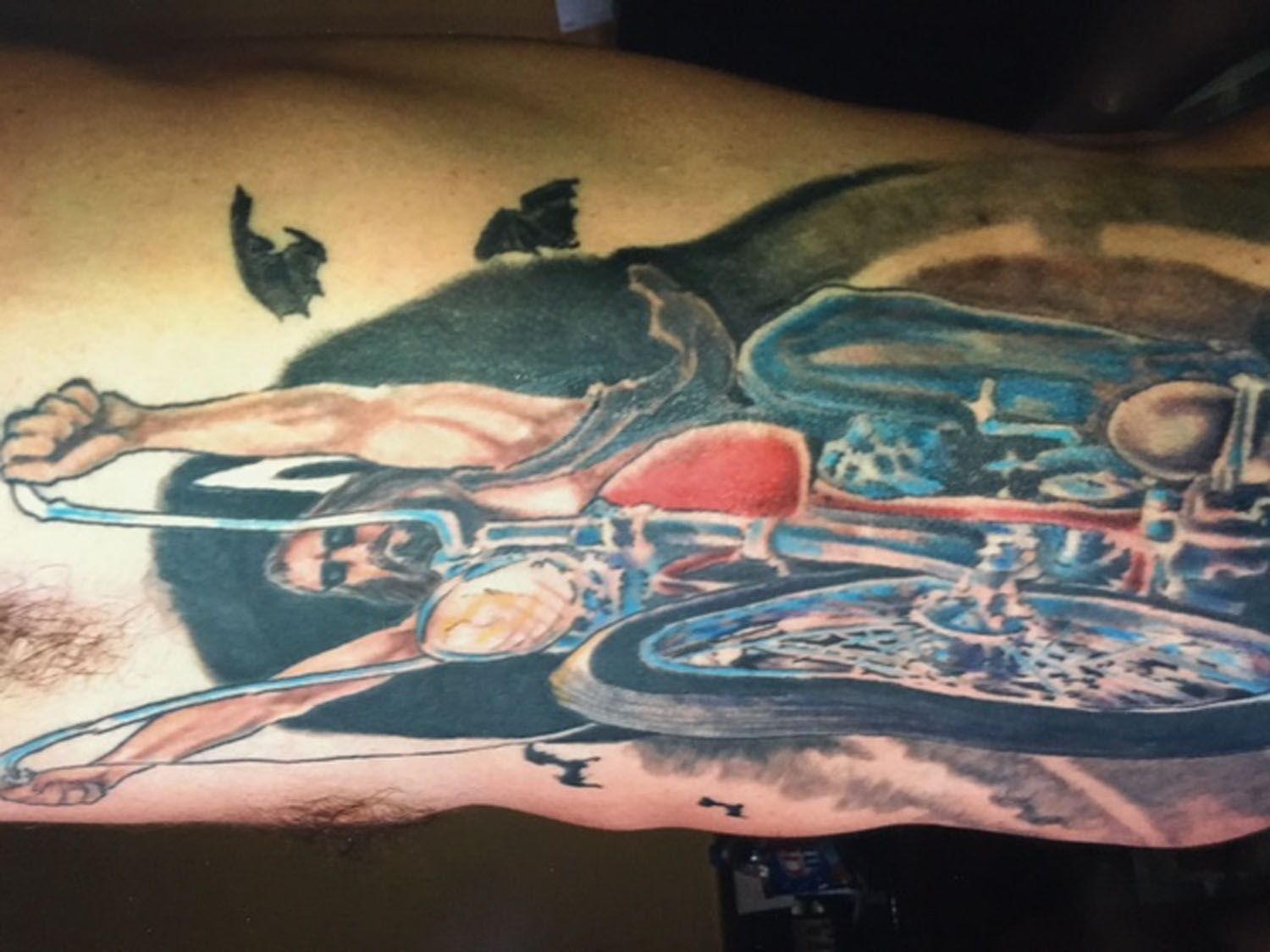 A tattoo of a man laying on a motorcycle