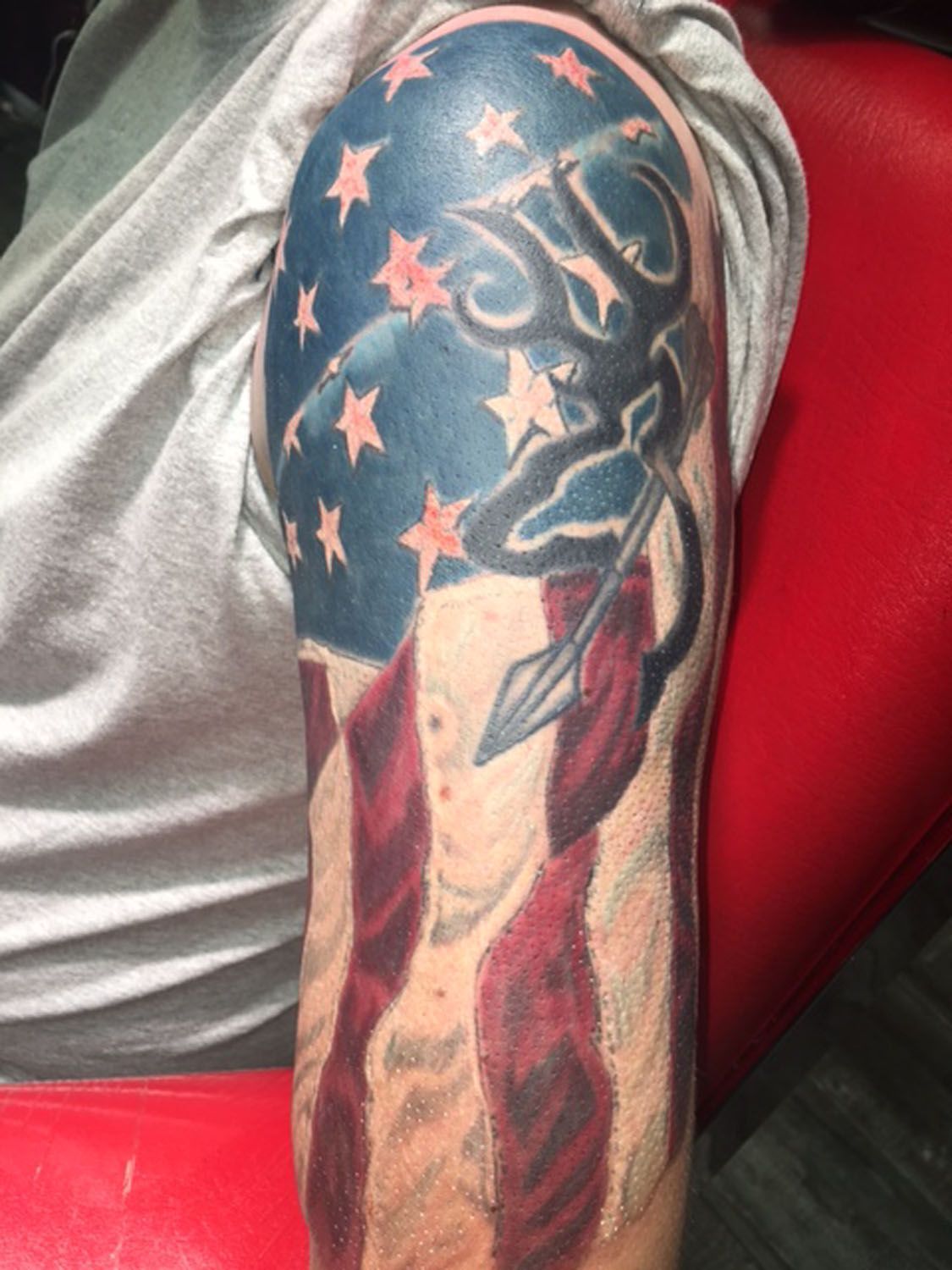 A man has a tattoo of an american flag on his arm.