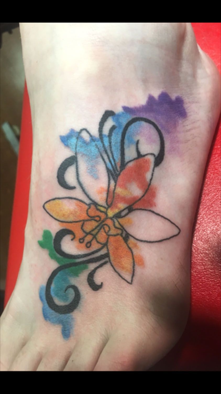 A person has a colorful flower tattoo on their foot