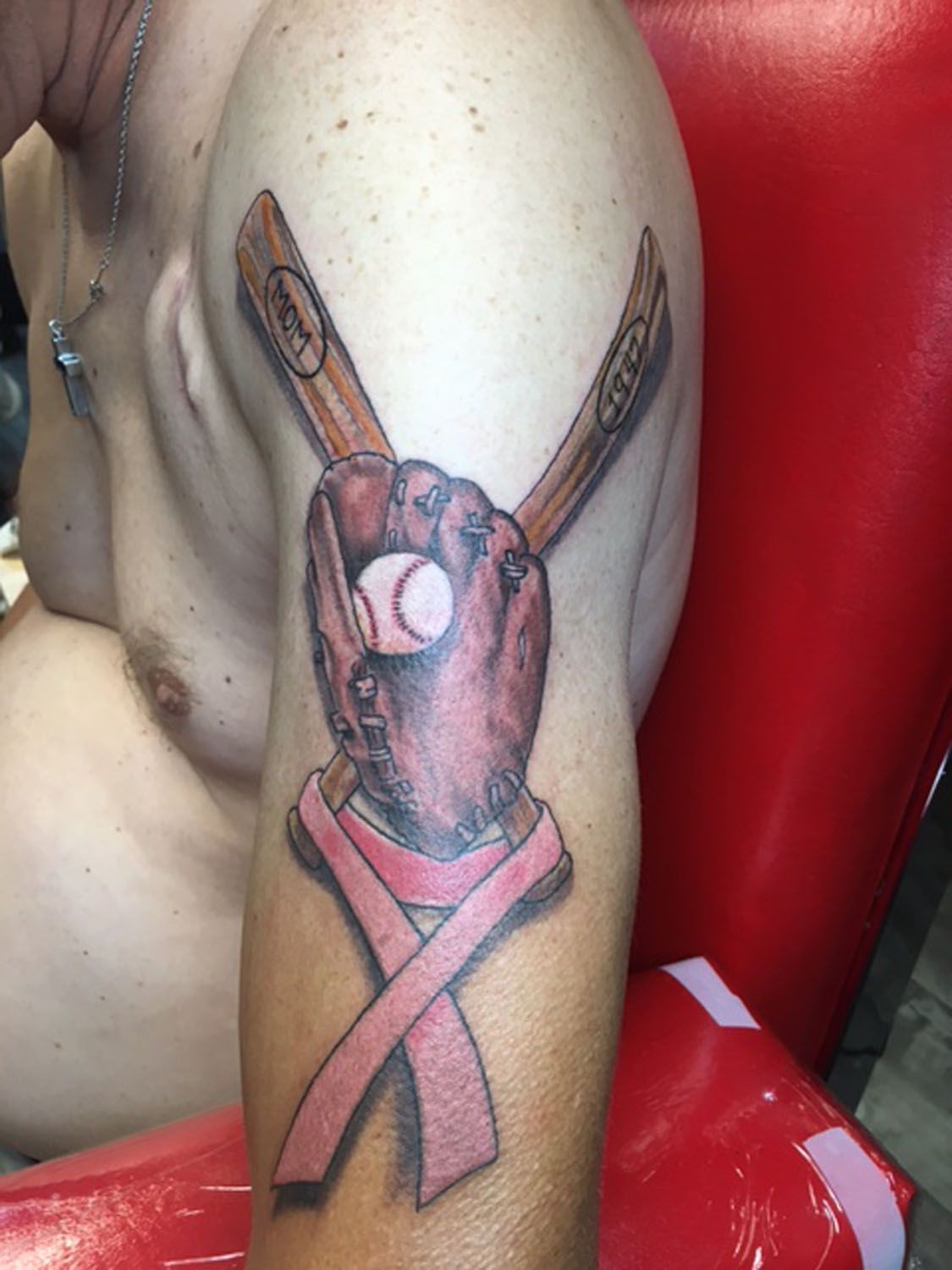A man has a tattoo of a baseball glove and bats on his arm.