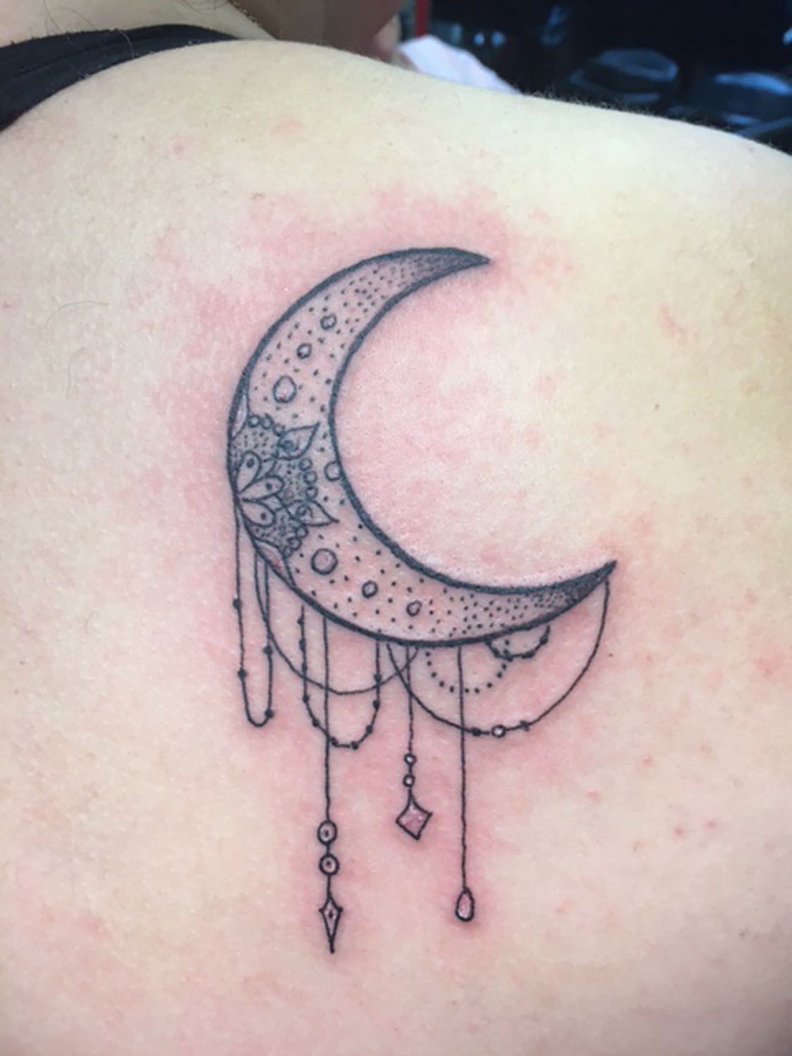 A woman has a tattoo of a crescent moon on her back