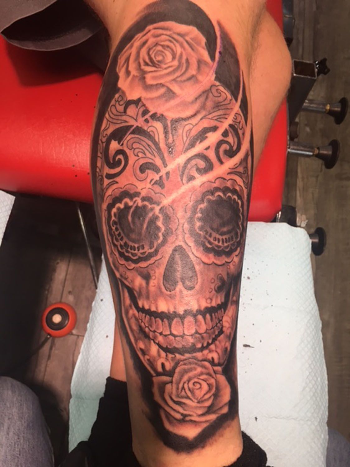 A person has a sugar skull tattoo on their leg