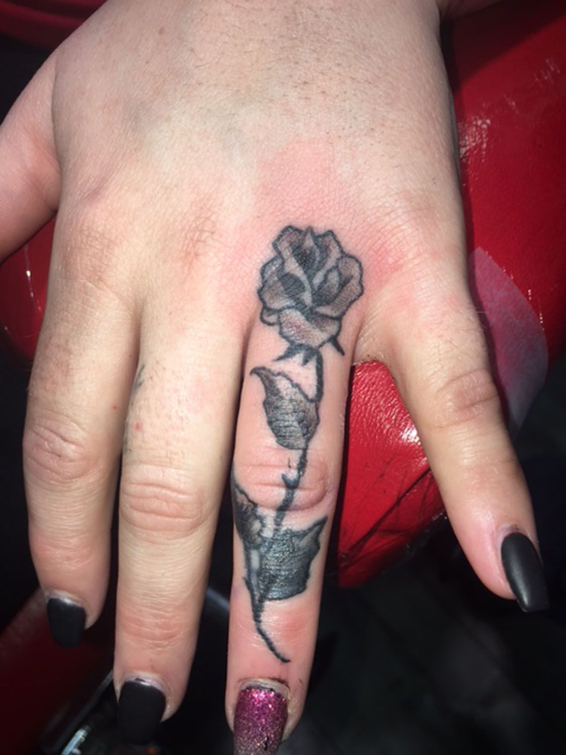 A woman has a tattoo of a rose on her thumb