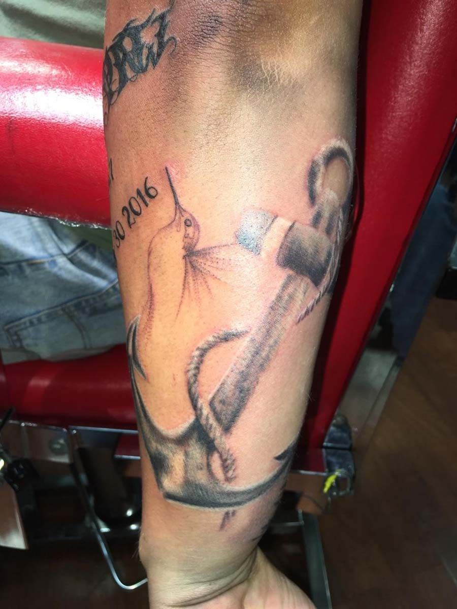 A man has a tattoo of an anchor on his arm.