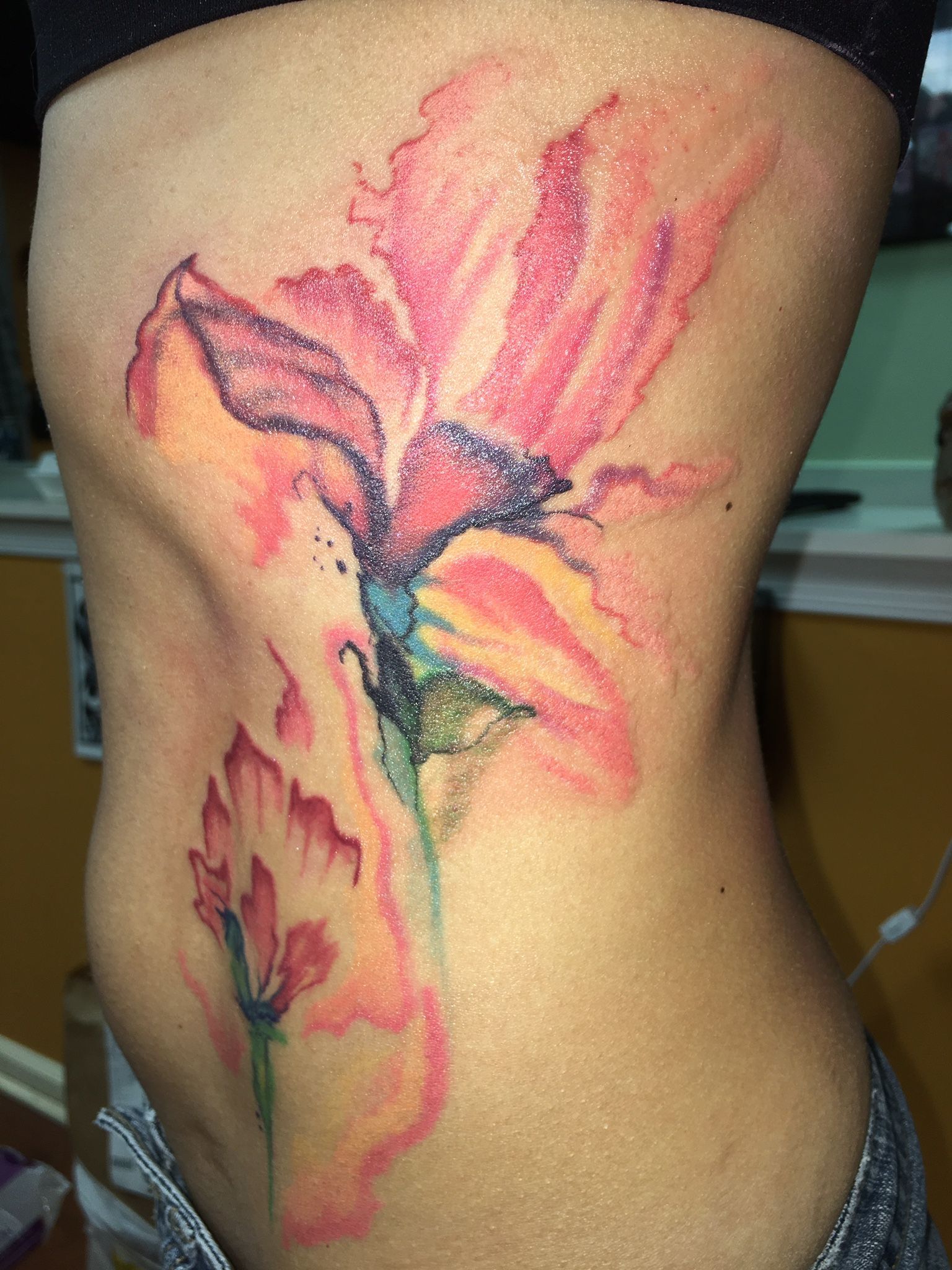 A woman has a tattoo of a flower on her side.