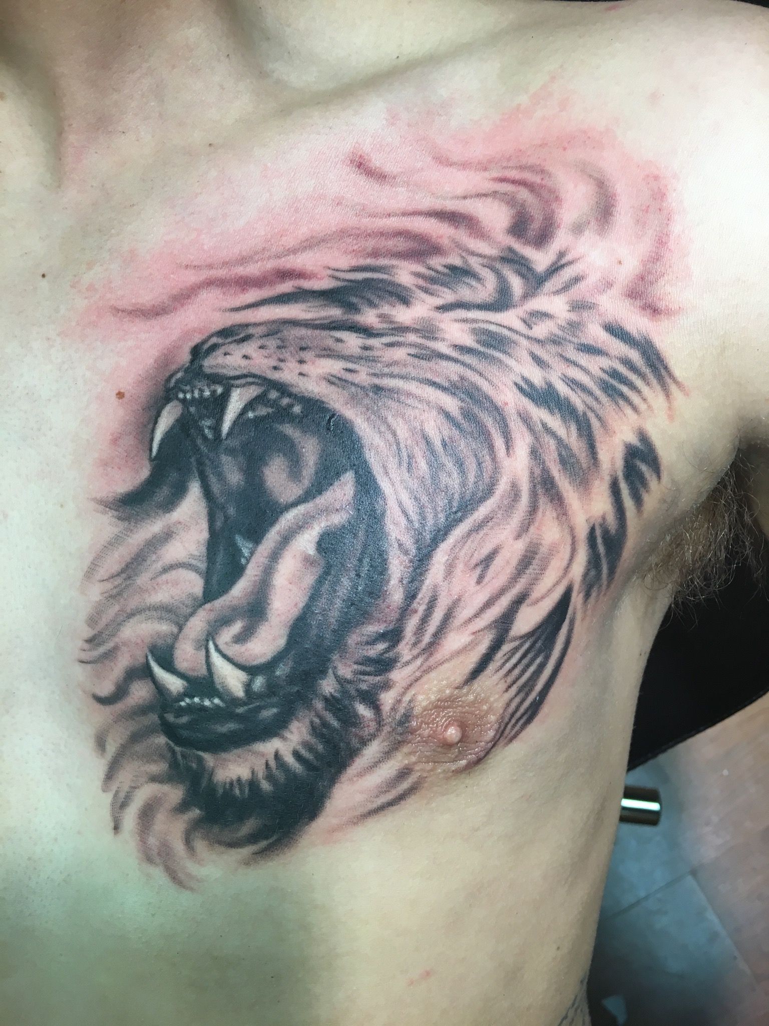 A man has a tattoo of a lion on his chest.
