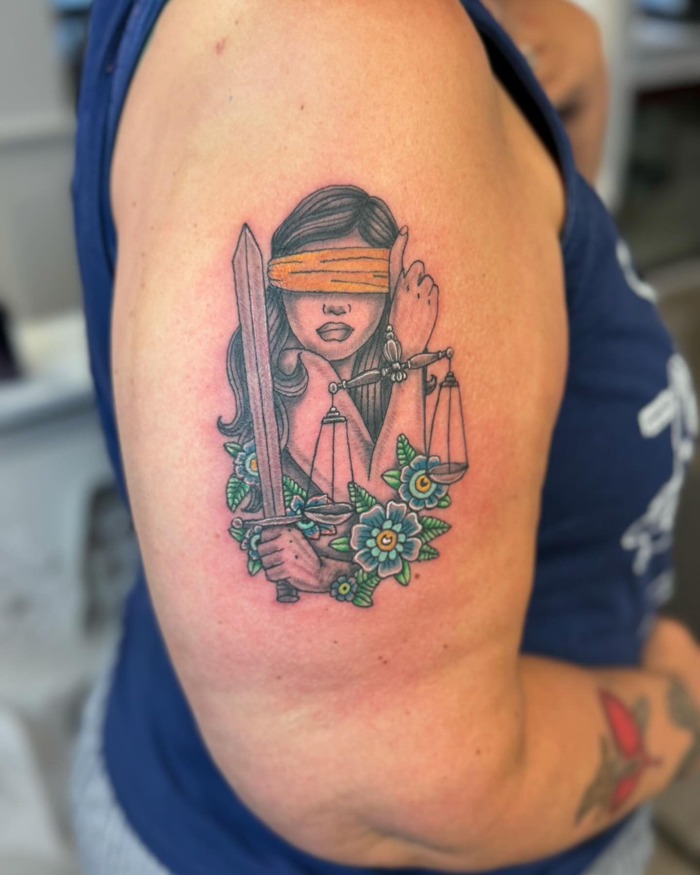 A woman has a blindfolded lady justice tattoo on her arm