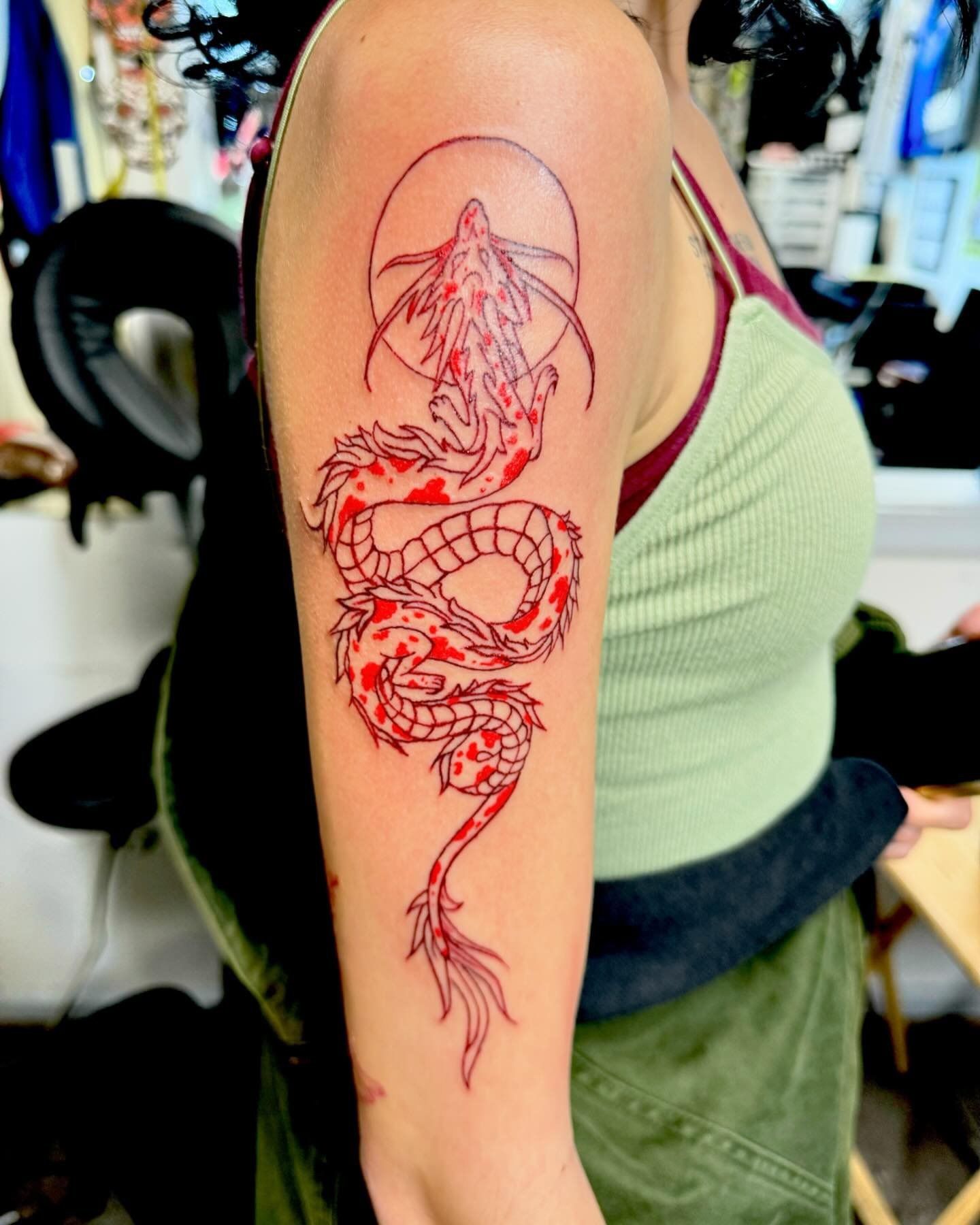 A woman has a red dragon tattoo on her arm.