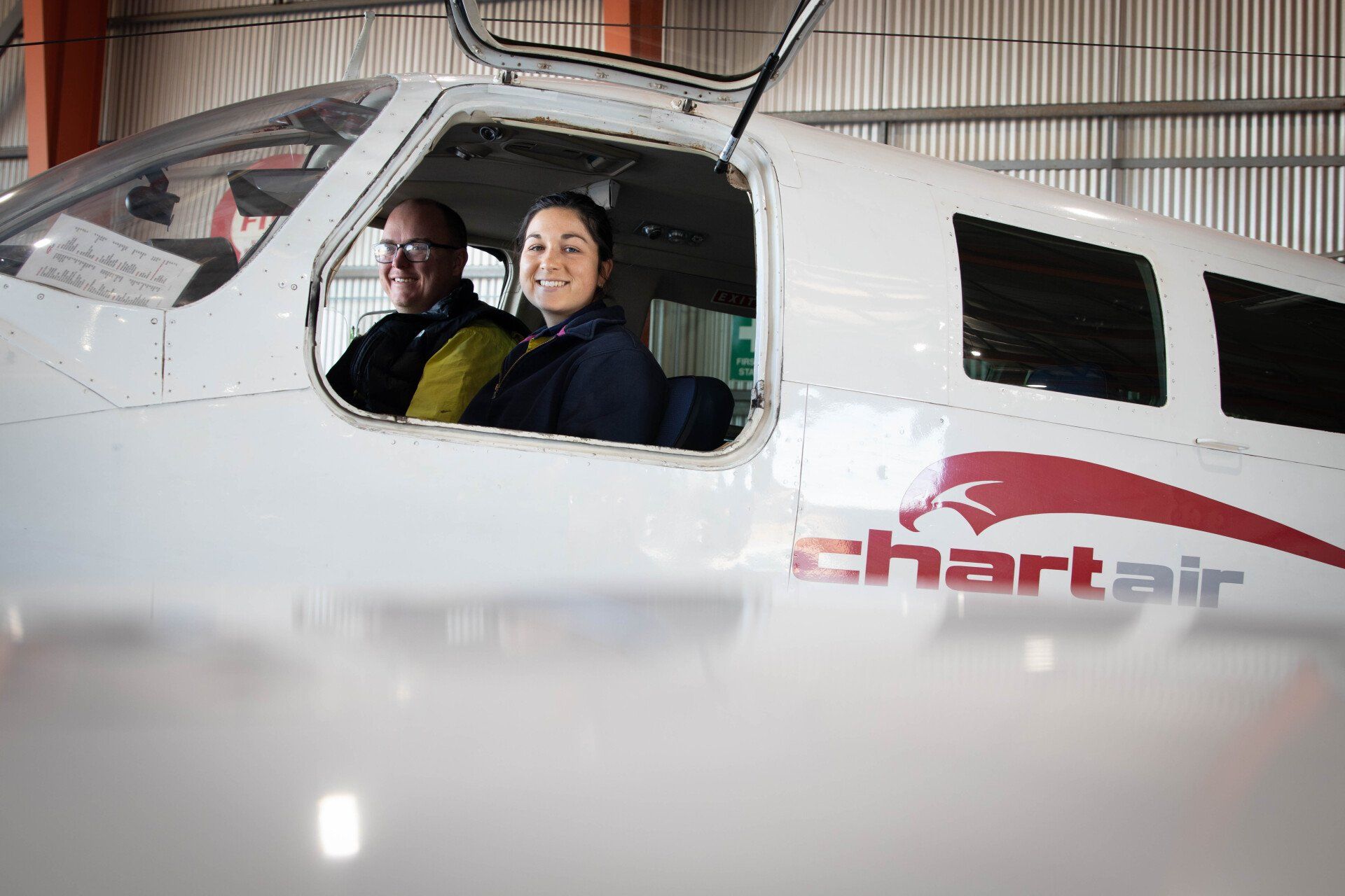 Two engineering staff sitting in a plane and smiling