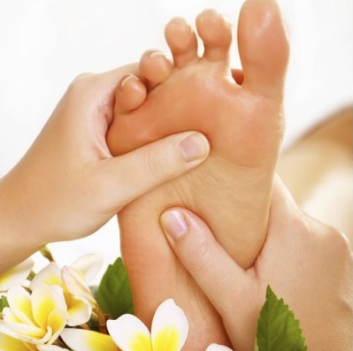Une personne reçoit un massage des pieds avec des fleurs en arrière-plan