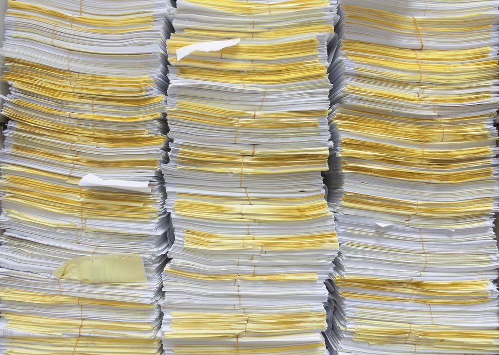 Pilas de papel blanco con bordes amarillentos, posiblemente documentos de archivo.