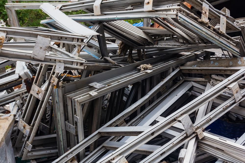 Pila de marcos de ventanas blancos y piezas de metal desechados.