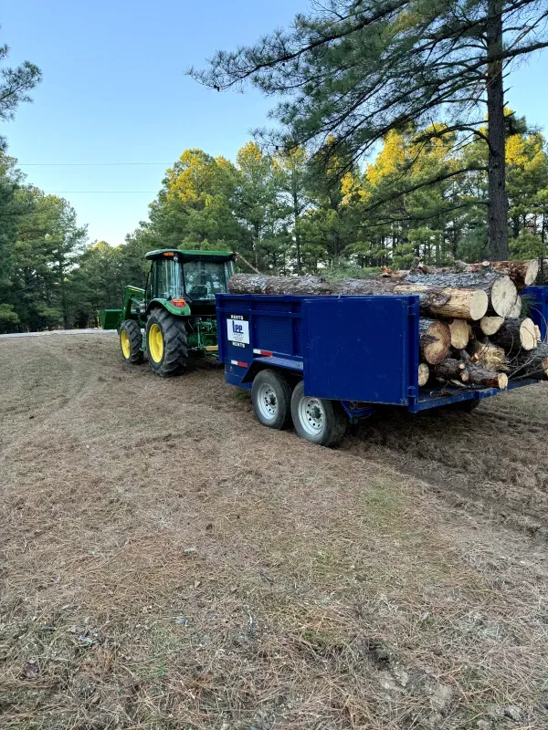 A tractor is pulling a trailer full of logs.