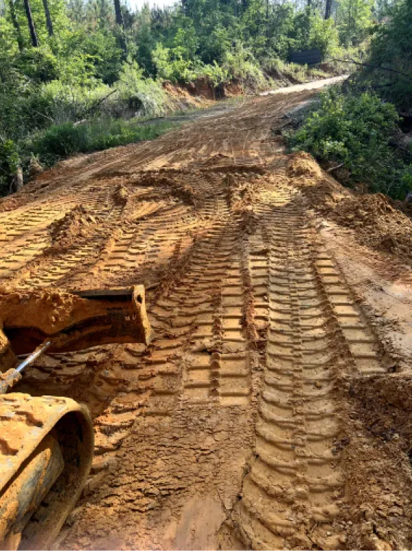 A bulldozer is driving down a dirt road.