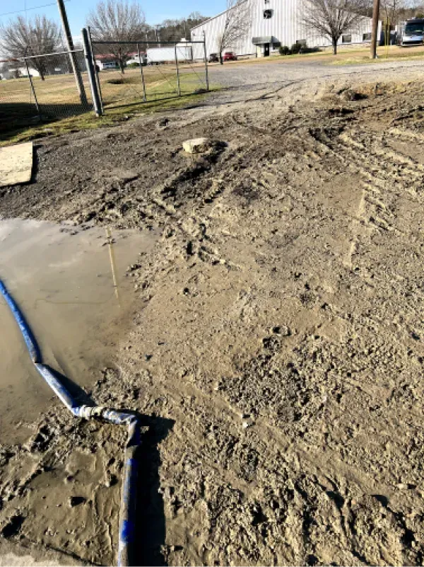 A muddy field with a hose in the middle of it.