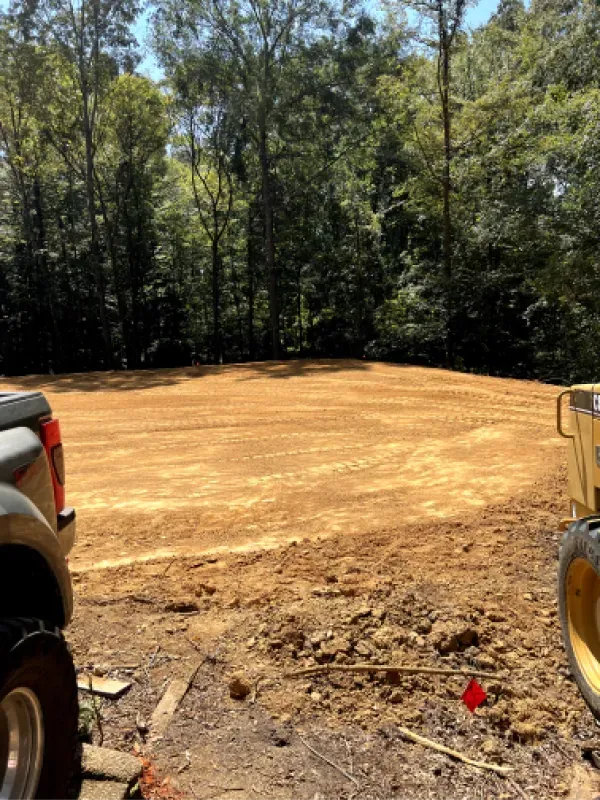 A truck is parked in a dirt field next to a dump truck.