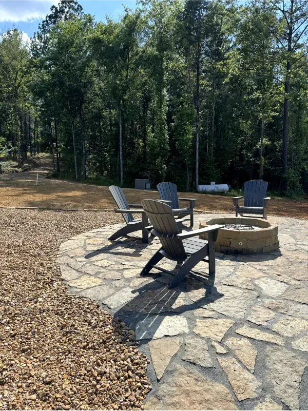 Two chairs are sitting next to a fire pit on a stone patio.