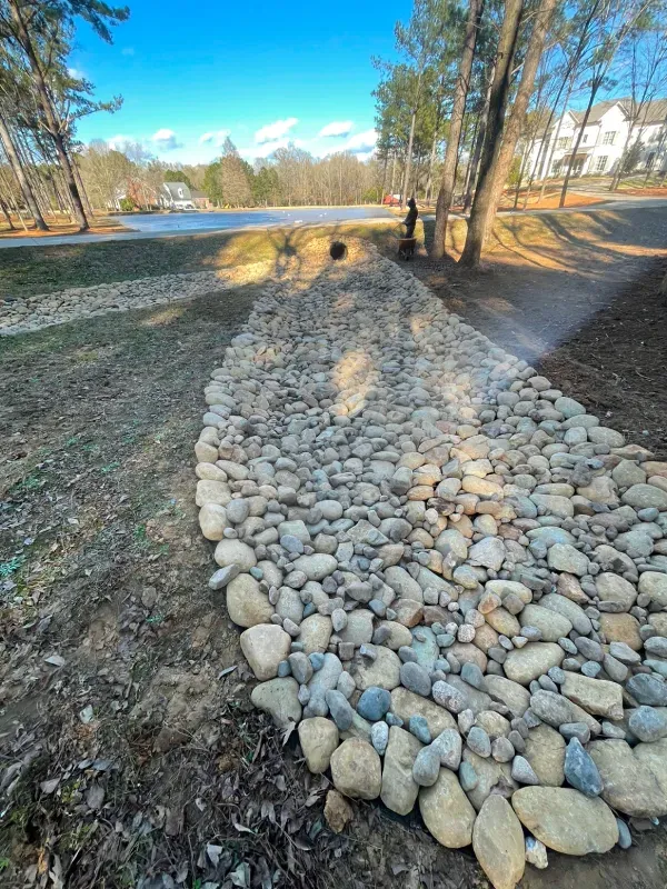 A pile of rocks on the side of a road next to a lake.