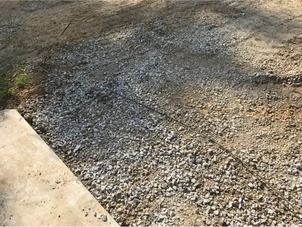 A pile of gravel is laying on the ground next to a sidewalk.