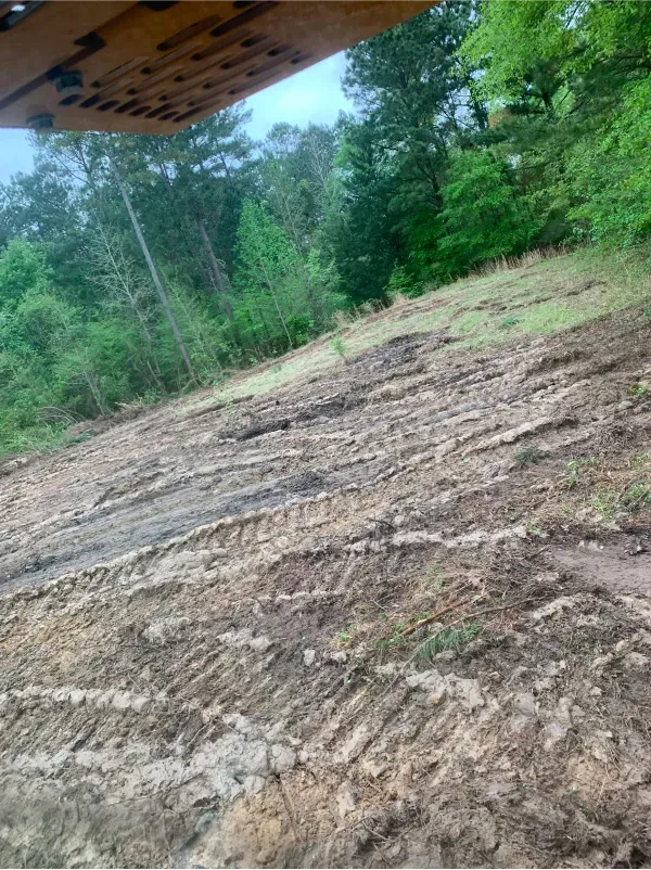 A large pile of dirt in a field with trees in the background.