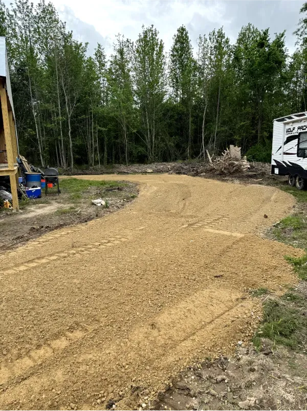 A dirt road with a trailer parked on the side of it.