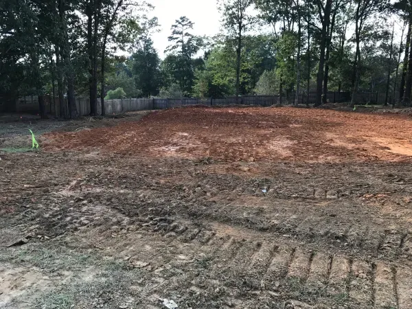 A large dirt field with trees in the background.