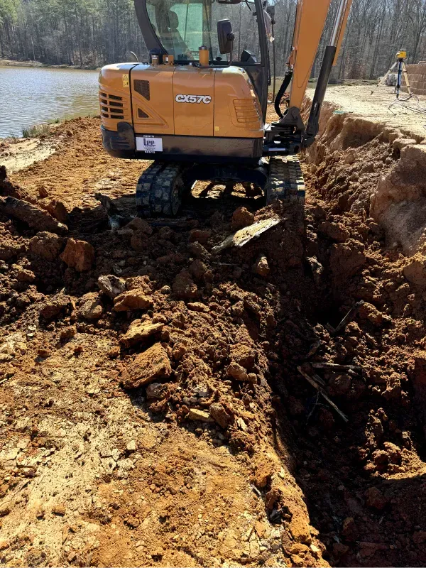 A case excavator is digging a hole in the dirt