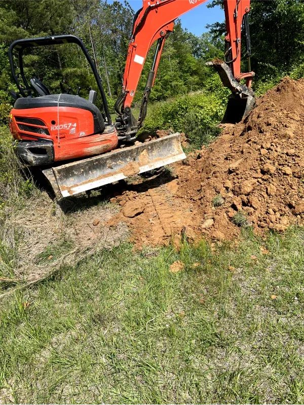 A red excavator is digging a hole in the dirt.