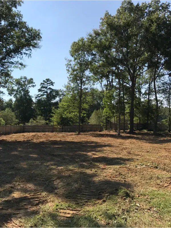A large dirt field with trees in the background