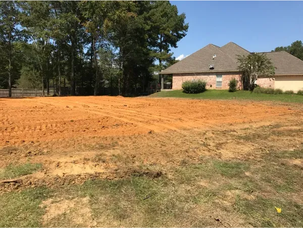 A dirt field with a house in the background