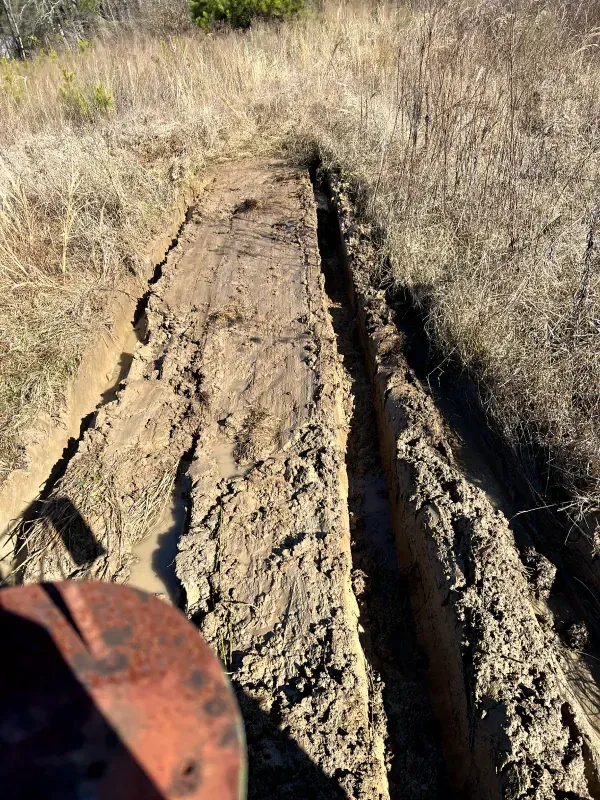 A person is driving a tractor through a muddy field.