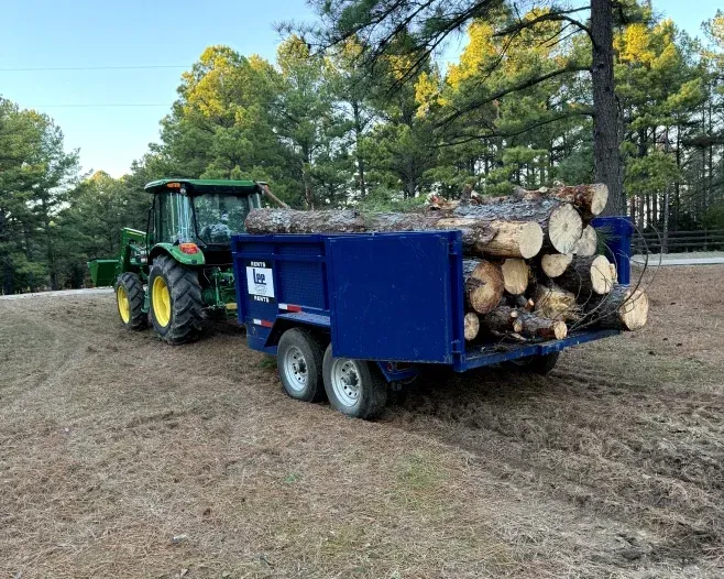 A tractor is pulling a trailer full of logs.