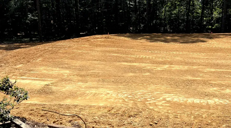 A large dirt field with trees in the background.