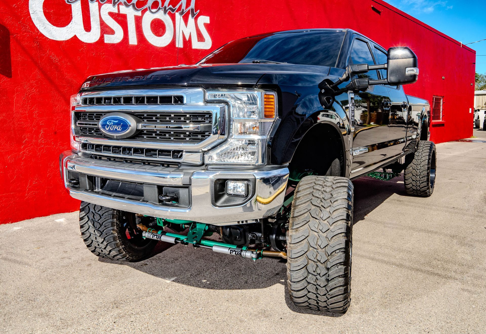 A black ford truck is parked in front of a red building.