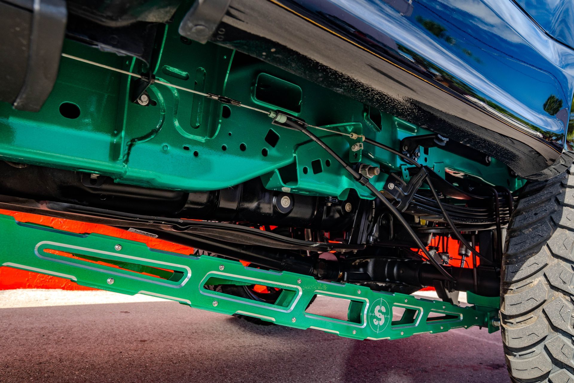 The underside of a blue truck with green and orange paint