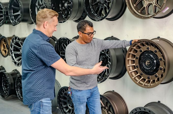 Two men are looking at a wheel in a store.