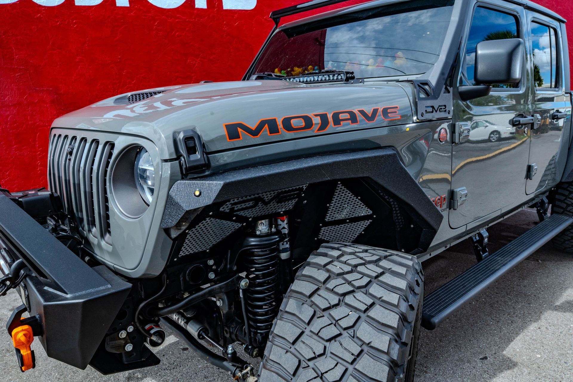 A jeep is parked in front of a red wall.