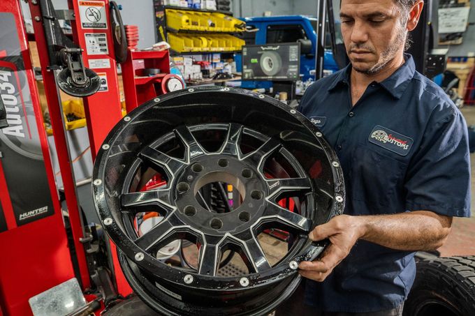 A man is holding a wheel in his hands in a tire shop.