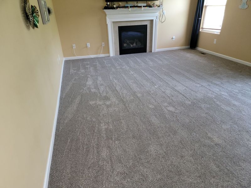 Empty beige living room with gray carpet and a fireplace