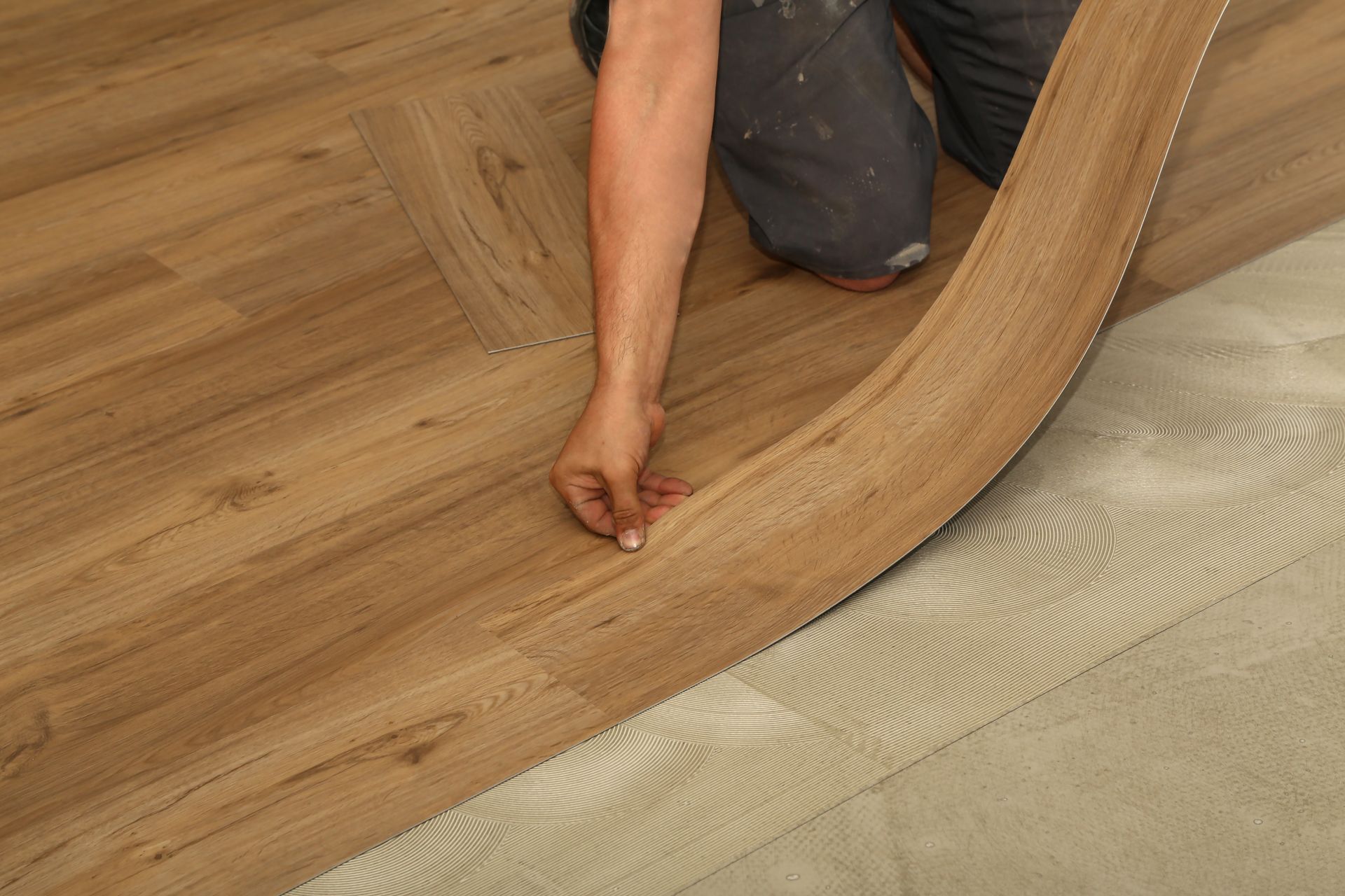 Person laying a wood-look floor plank over a cushioned underlayment during installation
