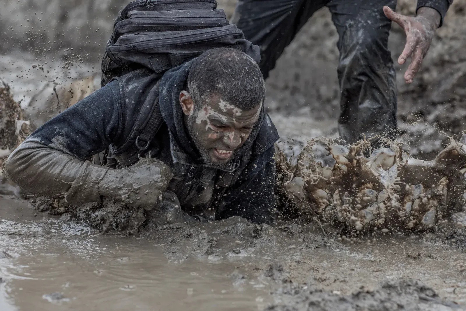 A man is crawling through a muddy puddle.