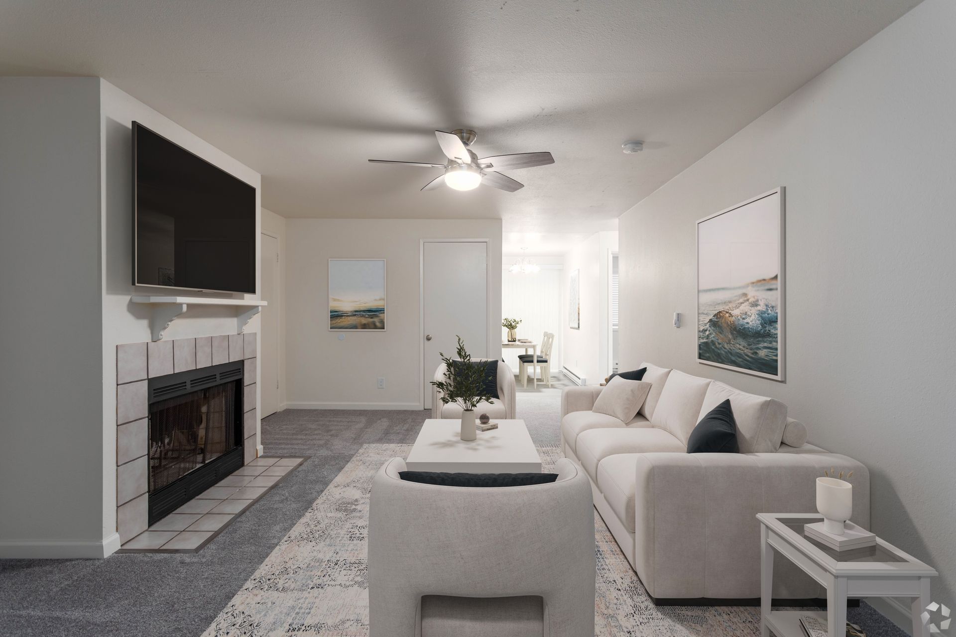 Living room with a fireplace, TV, white sofa, rug, and artwork.