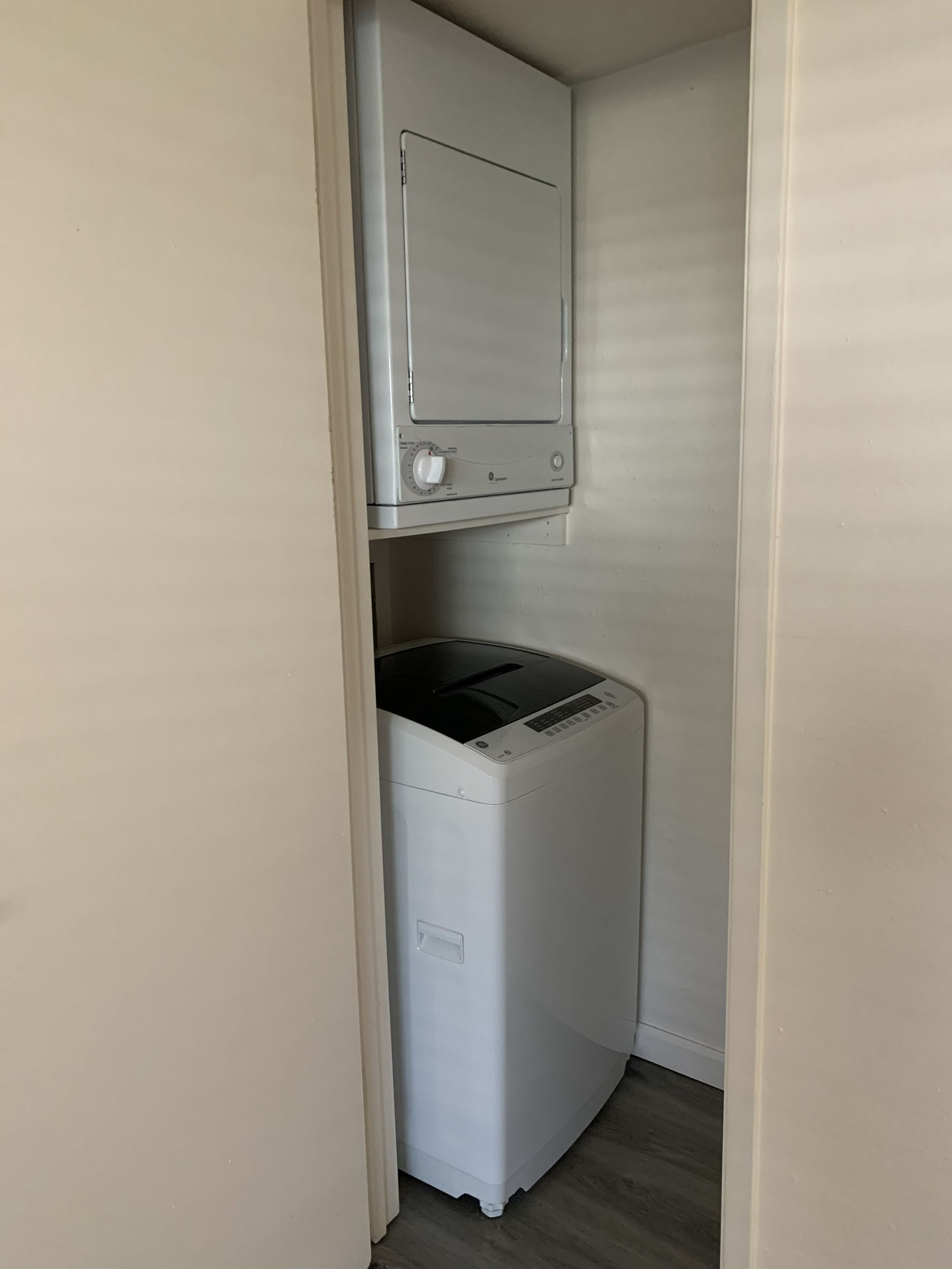 White stacked washer and dryer in a narrow closet.