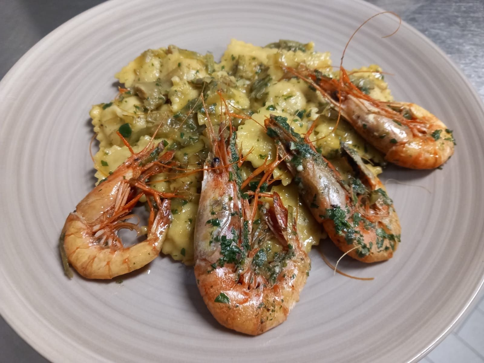 Due persone che tengono bicchieri di vino e un piatto di cibo davanti a un cartello che dice la playa