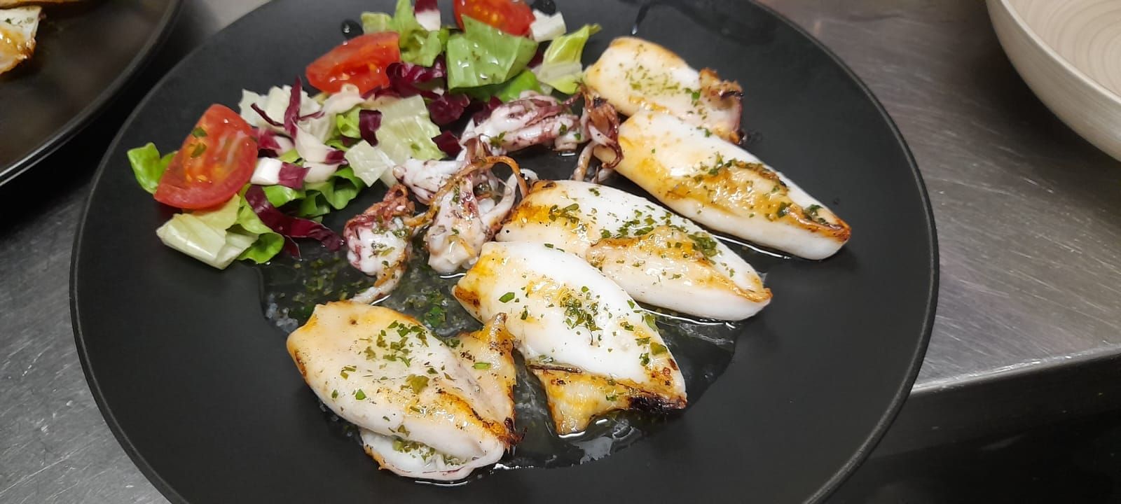 Un piatto di cibo e una bottiglia di vino su un tavolo.