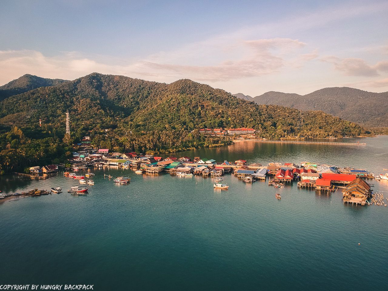 An aerial view of a small village in the middle of a lake with mountains in the background.