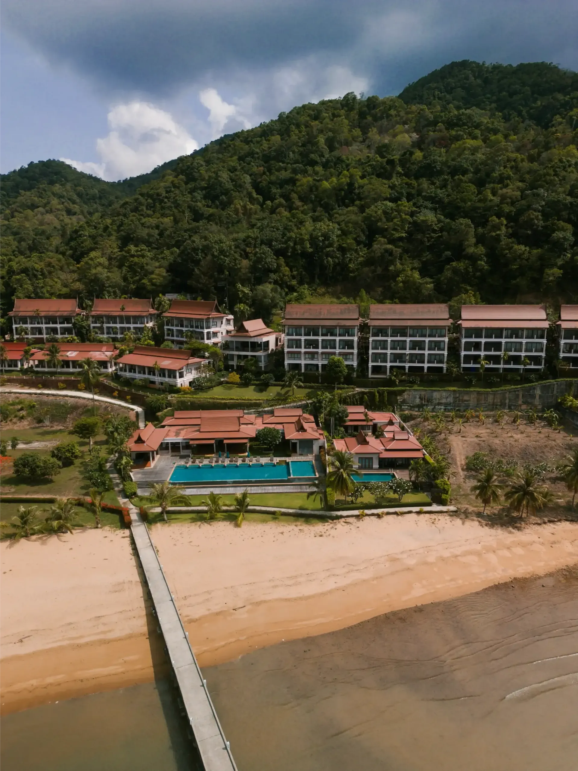 An aerial view of a beach resort with a dock leading to it.