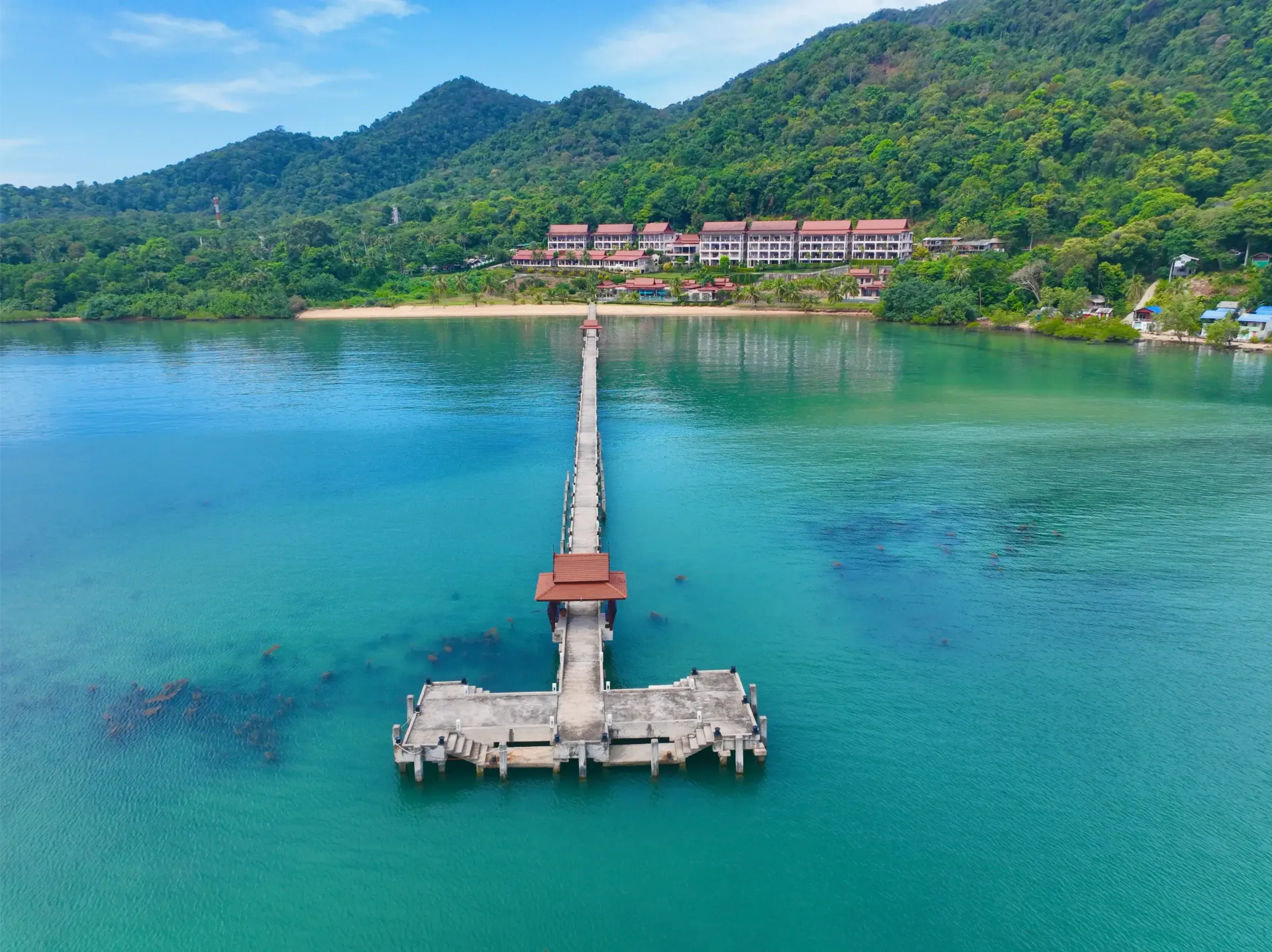 An aerial view of a wooden pier in the middle of the ocean.
